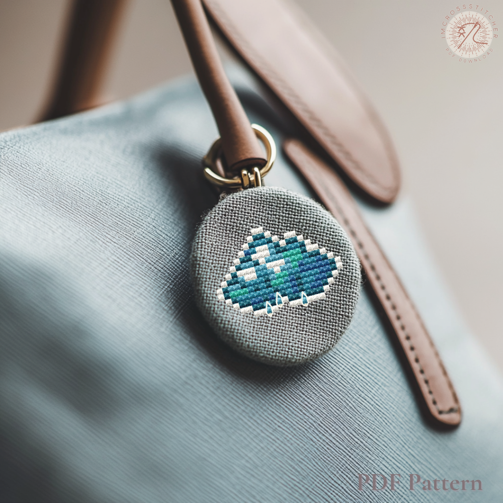 Small embroidered cloud charm attached to a handbag, made using a Lumi Mini Set cross stitch pattern.